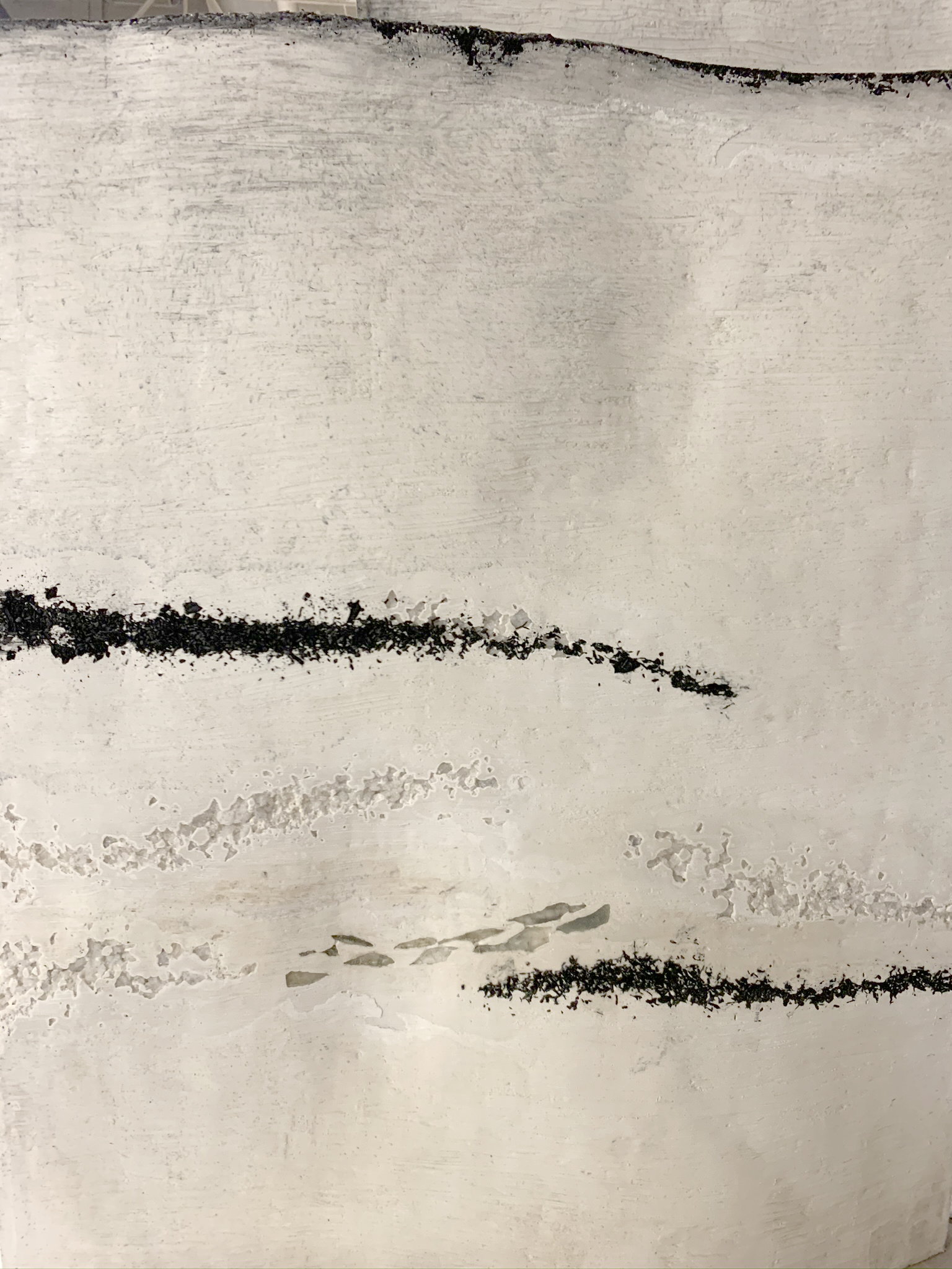 A close up of a white plaster panel with balck charcoal streaks embedded