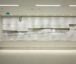 A view of Near Distance, a public art installation in the NEW SLC airport made of white plaster panels with balck charcoal streaks. Gaps between the panels are visible in the center of the rectangular form.